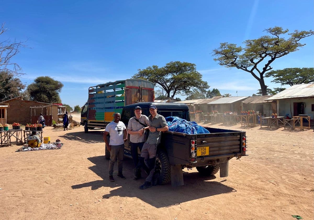 Three men standing next to a truck in a market area in Tanzania