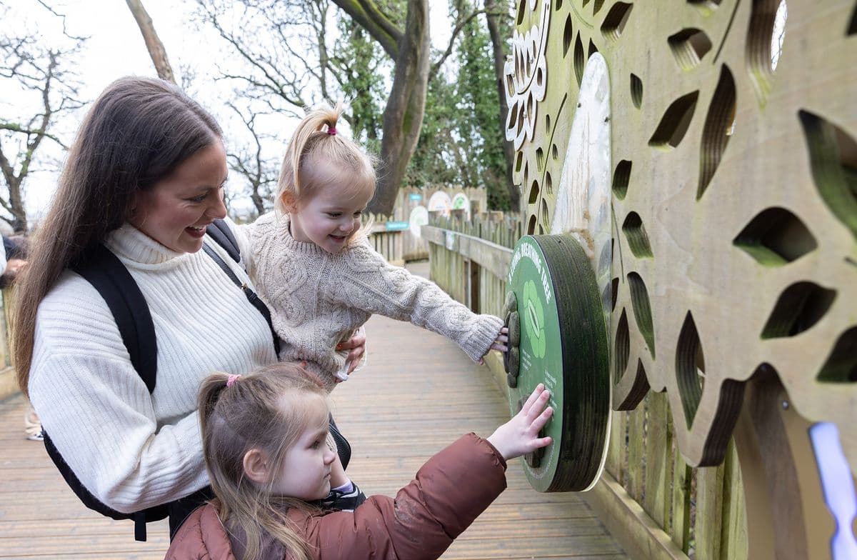 A young family happily looking at an info sign at the zoo