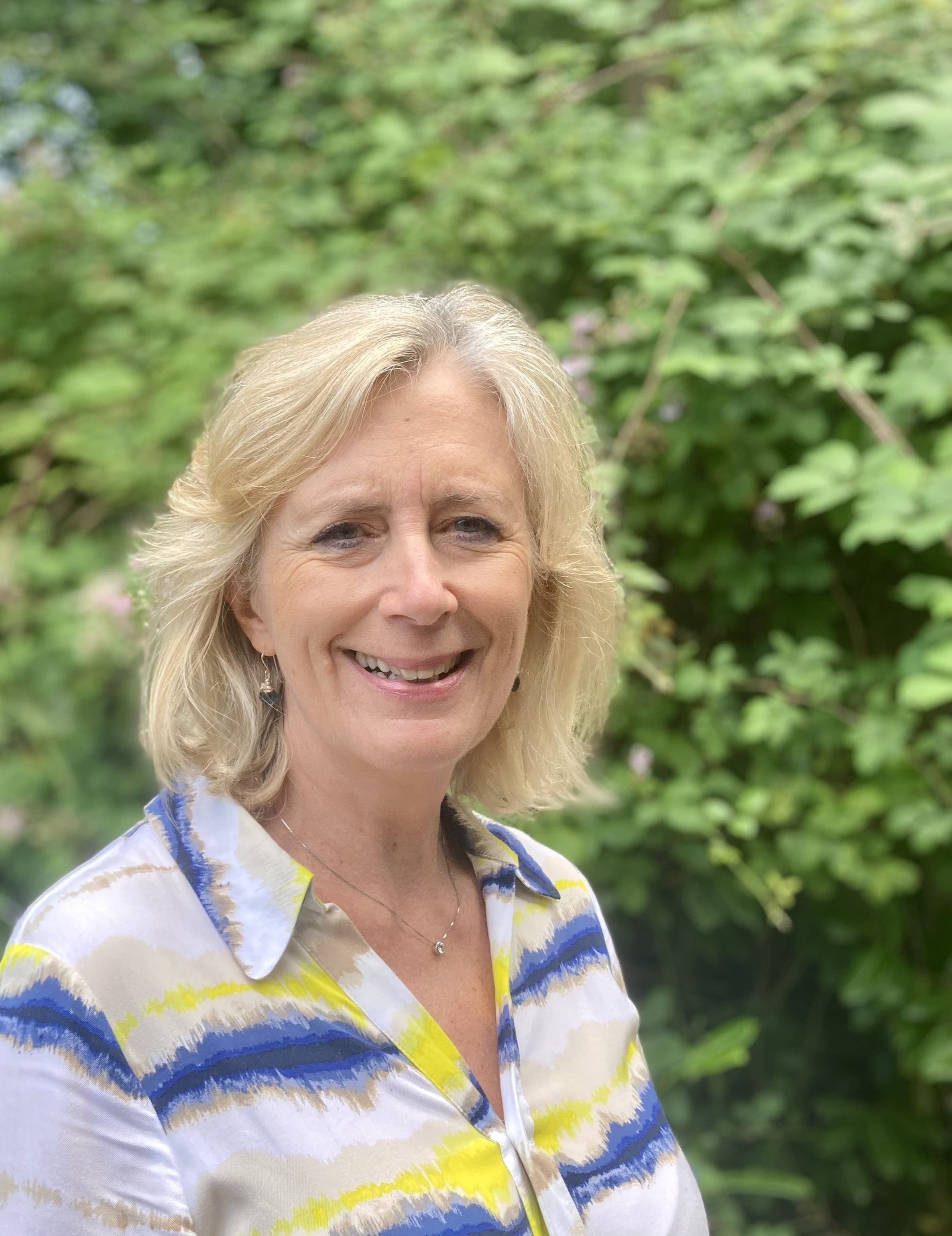 Head shot of Victoria Ash against a backdrop of greenery