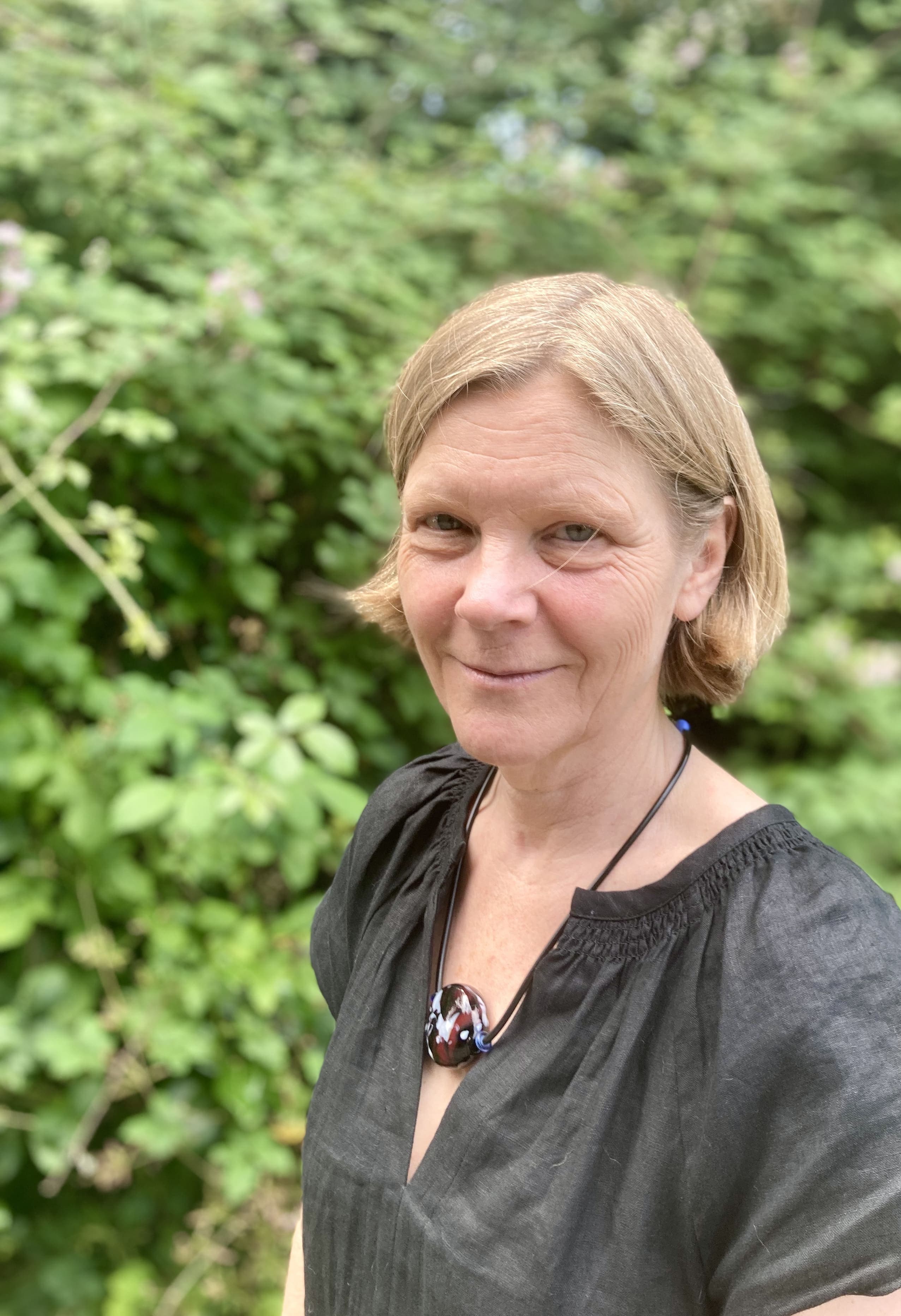 Head shot of Emma Woollett against a backdrop of greenery
