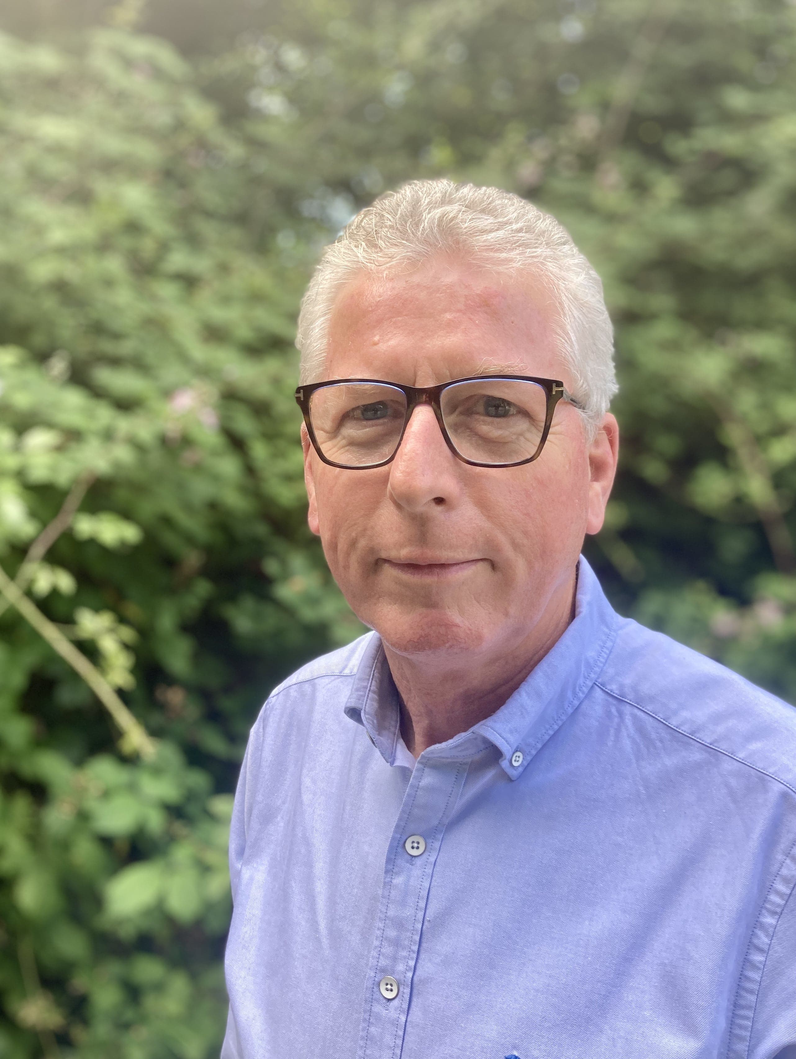 Head shot of David Esam against a backdrop of greenery